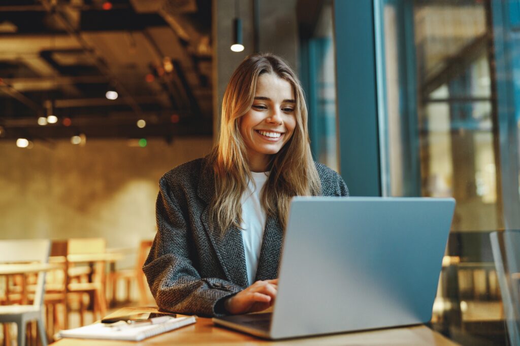 Smiling woman working confidently on her laptop, symbolizing renewed confidence and clarity from learning how to believe in yourself.