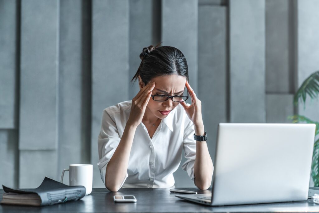 Stressed businesswoman at her desk holding her head in frustration while analyzing online results, questioning if SEO is worth it for small business.
