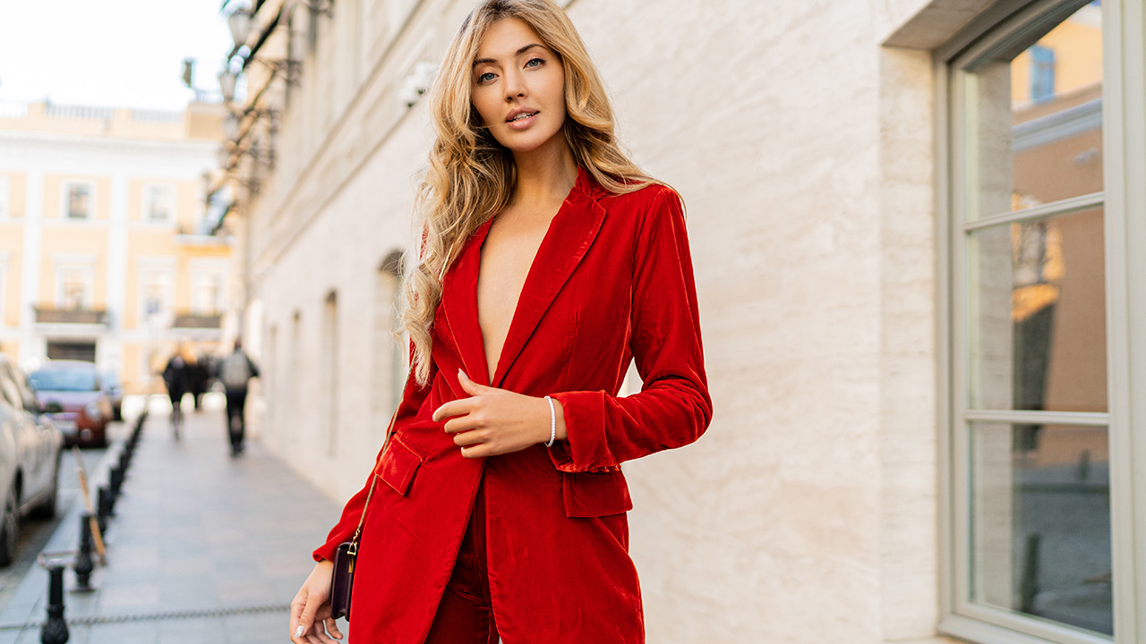 Confident woman in a red suit walking outdoors, representing powerful personal branding and self-expression in business.